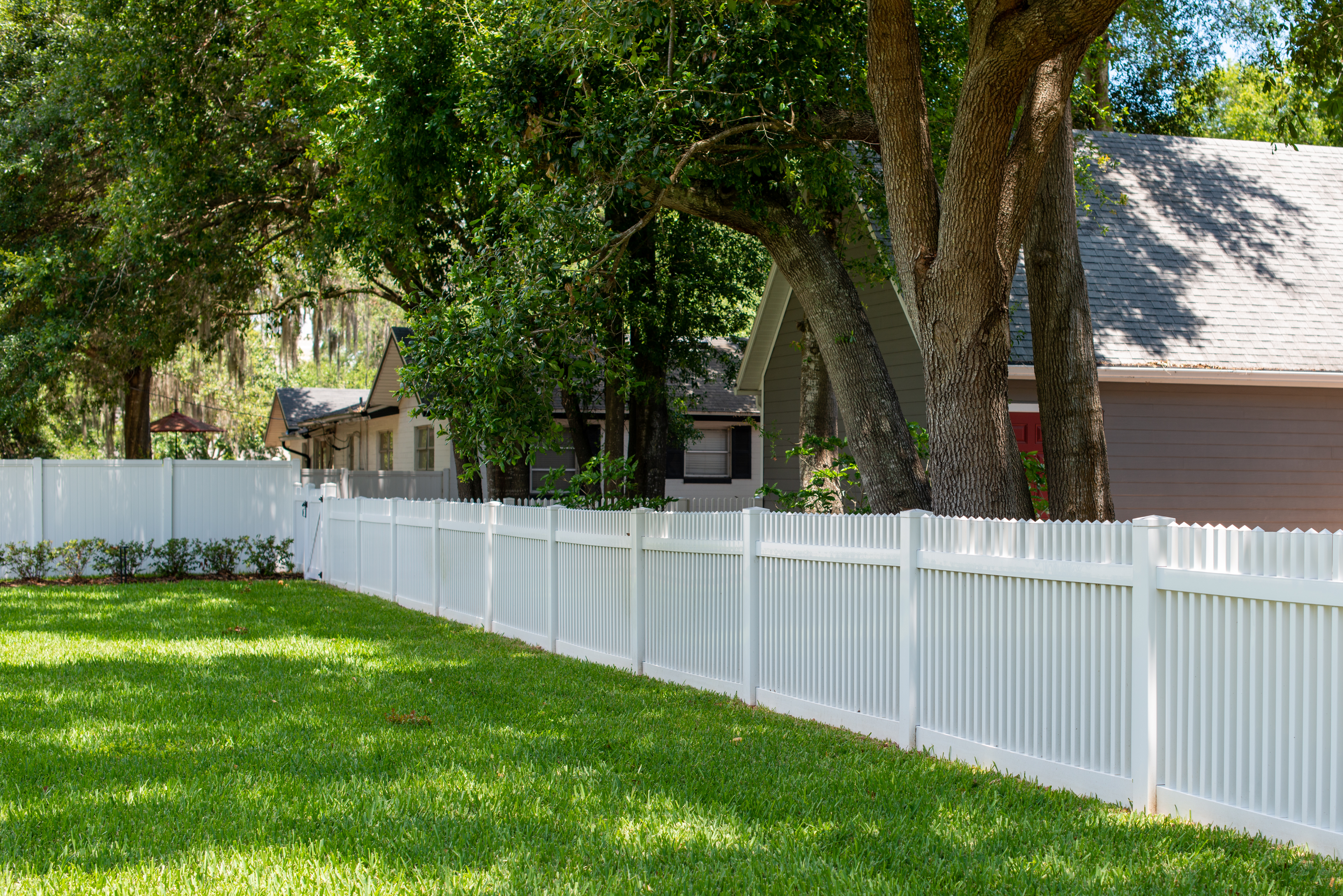 White vinyl fence along a lush green lawn in a Birmingham Alabama neighborhood — Total Home Fencing and Decks LLC